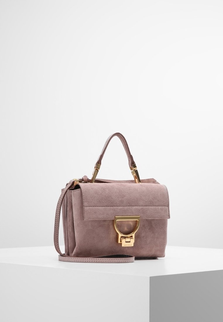 Pieni suorakulmainen käsilaukku pehmeästä vaaleanpunaisesta mokasta, jossa on läppä sulkemiseen. Varustettu kultaisilla yksityiskohdilla, yläkahvalla ja irrotettavalla olkahihnalla.