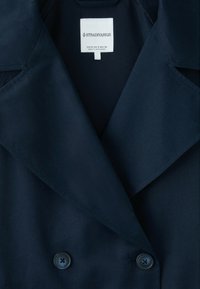 Navy blue double-breasted coat with wide lapels and two visible buttons, featuring a white Stradivarius brand label inside the collar.