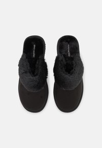 Sorte tøfler med overdel av faux pels og myk innredning, med et minimalistisk design og flat såle for komfort.
