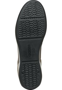 La suela de la zapatilla presenta un goma negra texturizada con surcos en forma de ola y agujeros de ventilación. La marca está grabada en la zona del talón.
