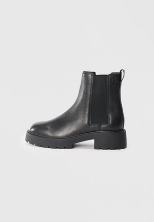 Botas Chelsea de cuero negro con una superficie texturizada, paneles laterales elásticos y suela de goma gruesa. Presenta un pequeño logo en el tacón.