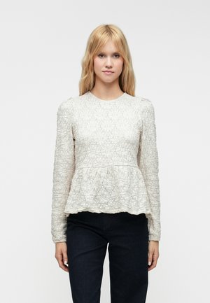 Svetlo bež peplum majica z dolgimi rokavi, izdelana iz teksturirane tkanine z cvetličnimi vzorci. Okroglo izrezovanje in rob s scalloped detajlom.