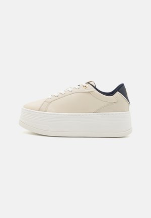 Beżowe sneakersy na platformie z białą podeszwą, górna część z gładkiej skóry, płaskie sznurowadła i granatowy akcent na pięcie. Detale w kolorze złotym.