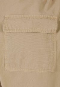 Poche en tissu beige avec bordure cousue, forme rectangulaire, texture lisse et sans matériel ou motifs visibles.