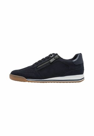 Lage zwarte sneaker met veterluiting, zijrits, geperforeerde zijkanten, witte tussenzool en bruine rubberen buitenzool.