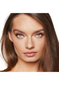 Primo piano di un volto con pelle liscia, trucco naturale e capelli castani lisci. Le caratteristiche notevoli includono occhi verdi e labbra piene.