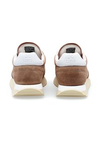 Un paio di sneaker in suede marrone con dettagli bianchi sul tallone, marchiate "LLOYD", viste da dietro su uno sfondo bianco.