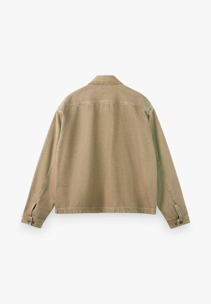Beige langärmelige Jacke mit knöpfbaren Manschetten, geradem Saum und sichtbaren Nähten über Rücken und Ärmeln, flach auf weißem Hintergrund liegend.