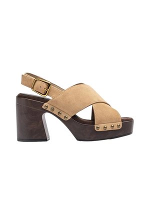 Chunky high-heeled sandal with light brown suede cross straps, gold buckle, decorative studs, and dark wooden platform heel.