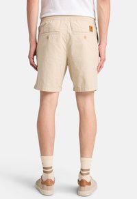 Bermuda khaki con vestibilità rilassata, realizzate in tessuto leggero, con due tasche posteriori con chiusura a bottone e un'etichetta del marchio.