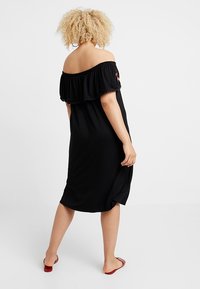 Czarna sukienka bez ramiączek z falbaniastym dekoltem, luźny krój, do kolan, wykonana z miękkiego materiału, z delikatnymi akcentami haftu florystycznego.