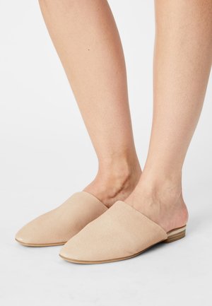 Scarpe slip-on in suede beige con punta affusolata, tacco in legno basso e texture liscia, caratterizzate da un design con schienale aperto per una facile indossabilità.