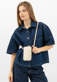 Camicia di jeans a maniche corte con bottoni sul davanti, abbinata a una borsa a tracolla in pelle color crema. Design casual con tasca frontale.