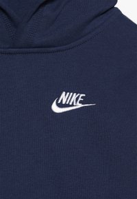 Sudadera azul marino con un logo de Nike bordado en blanco en el pecho. Fabricada con una tela suave de textura lisa y capucha ajustable.