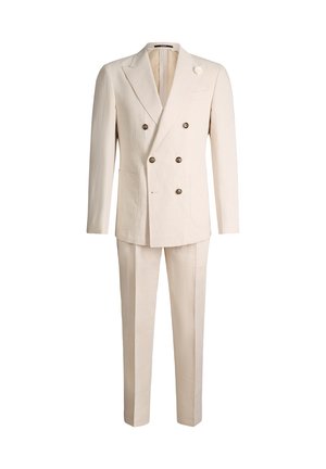 Costume croisé crème avec revers à pointe, six boutons, poches plaquées et pantalon assorti, présenté sur fond blanc.