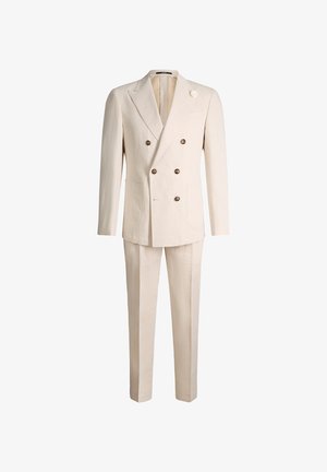 Costume croisé crème avec revers à pointe, six boutons, poches plaquées et pantalon assorti, présenté sur fond blanc.