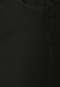 Jeans de mezclilla negra con un diseño estándar de cinco bolsillos, una textura suave y un color consistente. Sin logotipos ni adornos visibles.