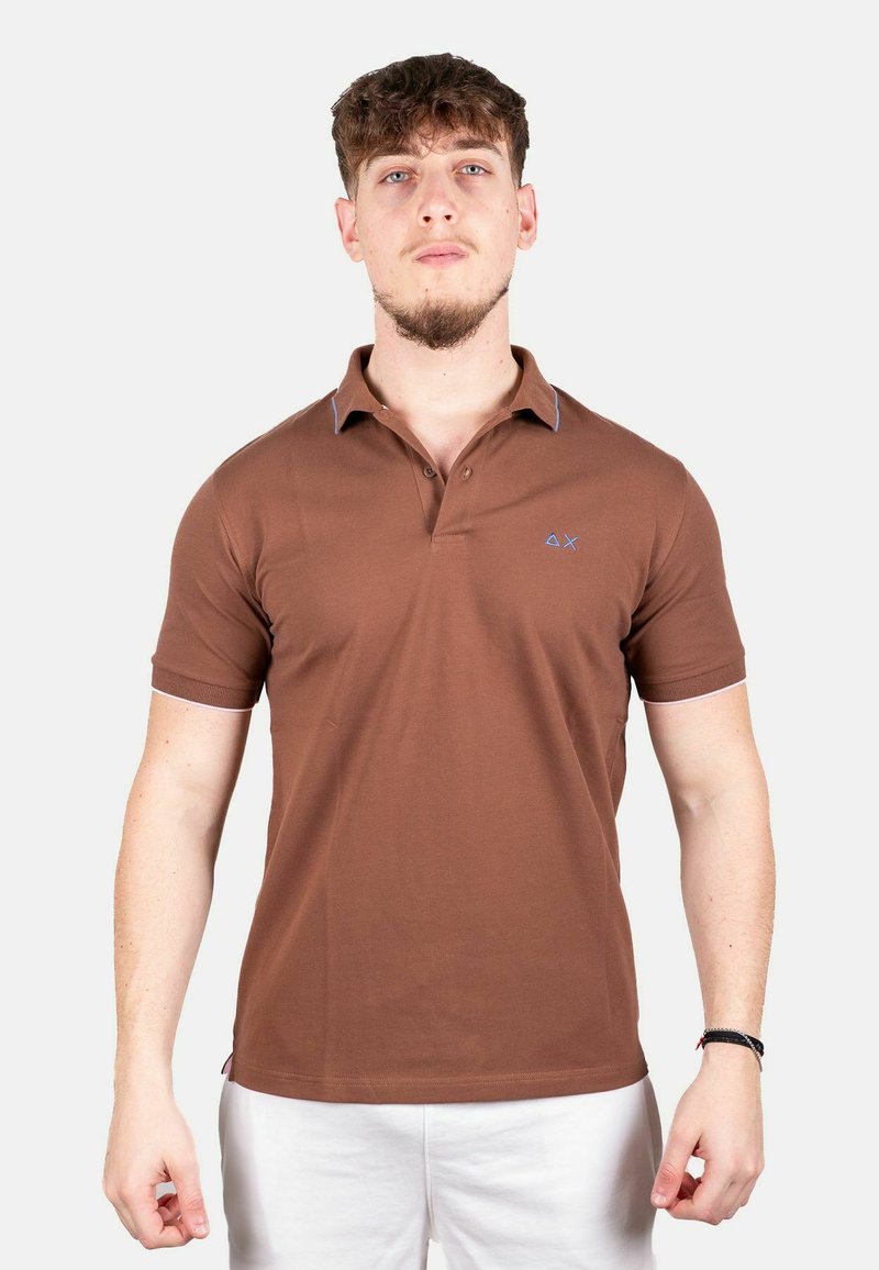 Bruine polo met korte mouwen, contrasterende blauwe accenten op de kraag en een kleine geborduurde logo op de borst.
