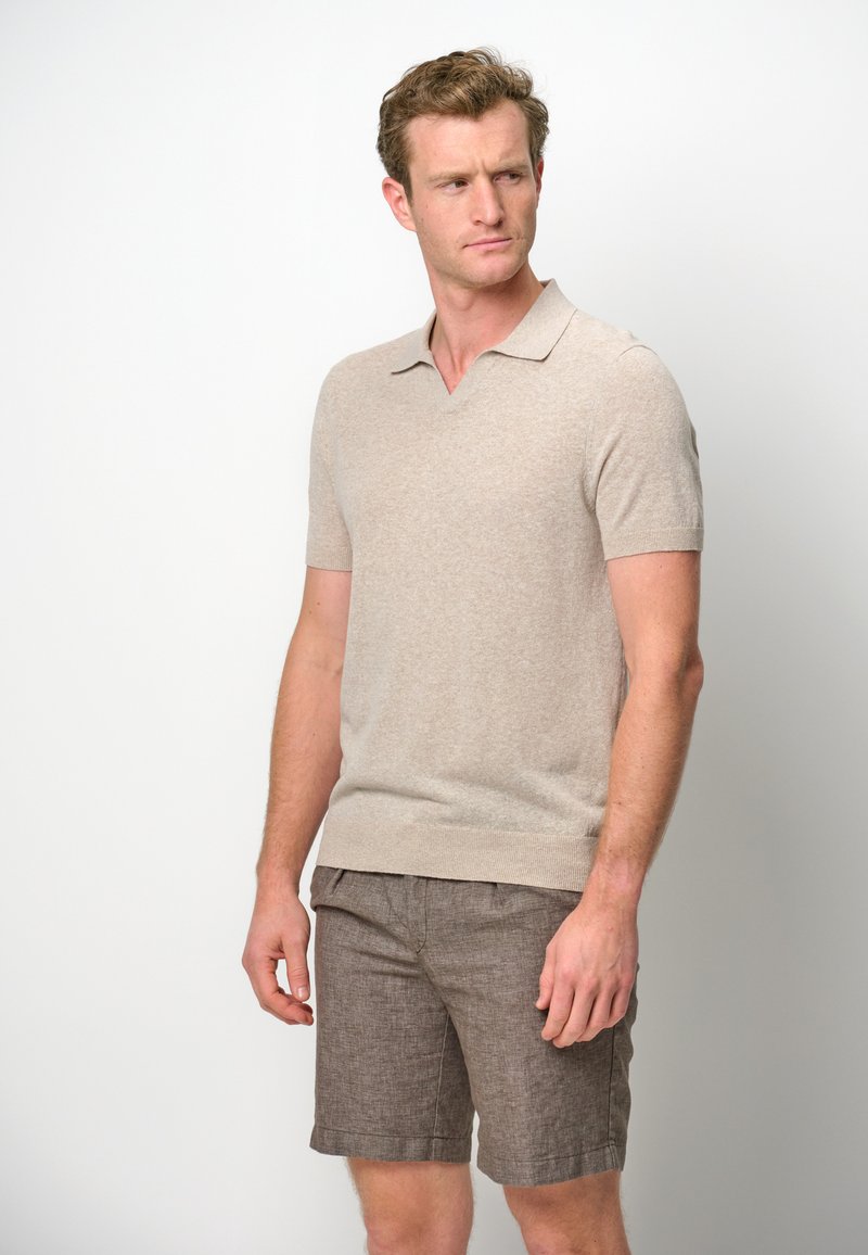 Short-sleeve beige knitted polo shirt with a V-neck and ribbed hem, paired with brown textured shorts featuring a rolled cuff.