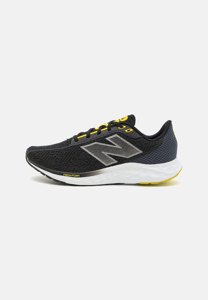 Zapato deportivo negro con parte superior de malla, acentos grises, cordones amarillos y una entresuela blanca acolchada con la marca "Fresh Foam" en el lateral.