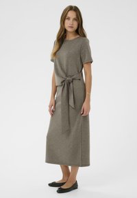 Siva midi obleka s kratkimi rokavi, detajl z veznikom na pasu, mehak material in raven kroj. Zraven so črne ravne čevlje.