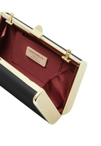 Pochette en cuir noir avec quincaillerie de ton doré. L'intérieur comprend une doublure en satin rouge et une étiquette. Le design inclut une fermeture à boucle.