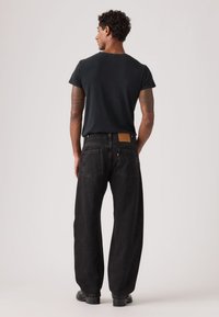 Μαύρο τζιν από τζιν υλικό με άνετη εφαρμογή, διαθέτει δύο πίσω τσέπες και ενισχυμένη ραφή. Συνδυάζεται με απλό μαύρο μπλουζάκι.