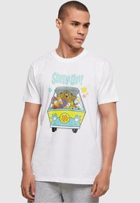 Hvit bomull t-skjorte med et fargerikt "Scooby-Doo"-grafikk med en varebil og tegneseriefigurer, satt mot en lys grå bakgrunn.
