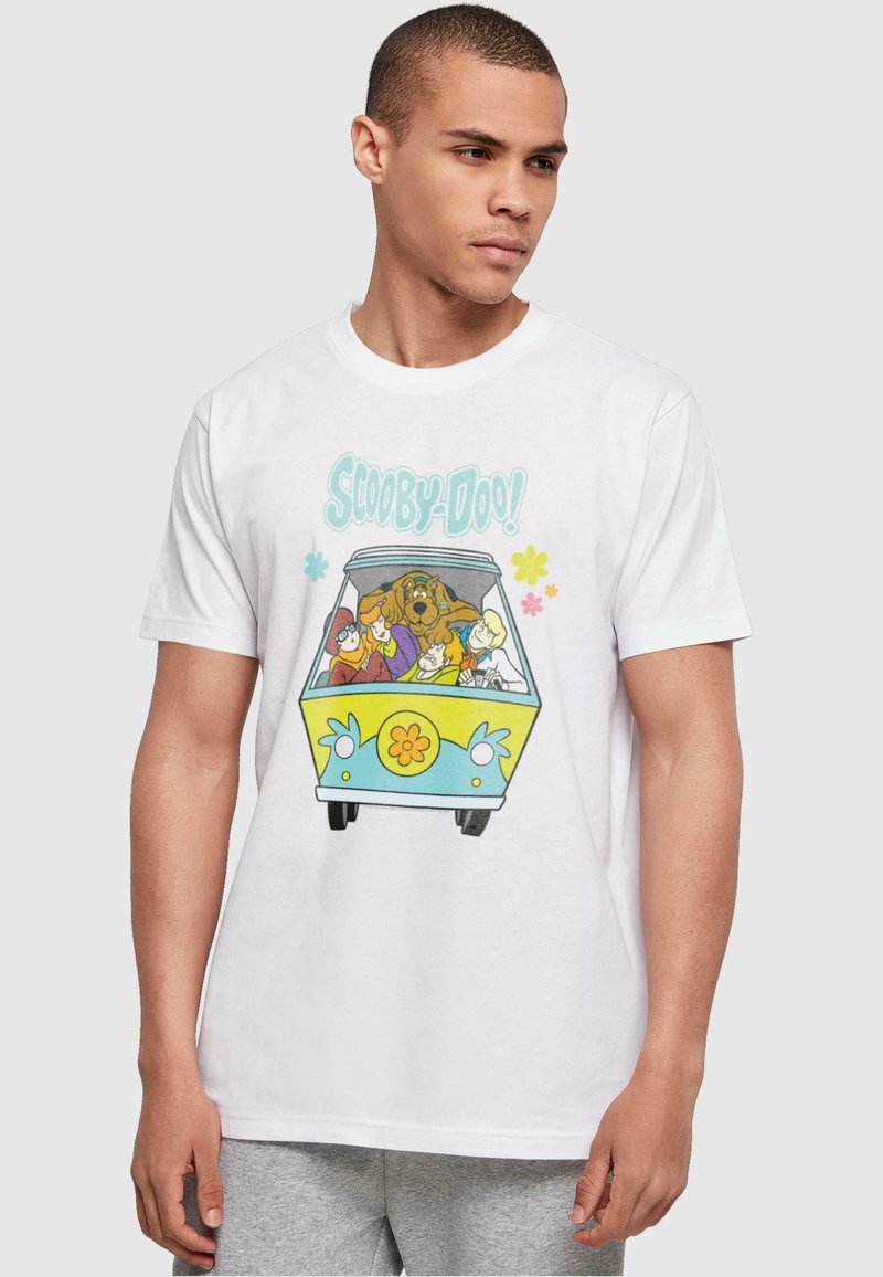 Hvit bomull t-skjorte med et fargerikt "Scooby-Doo"-grafikk med en varebil og tegneseriefigurer, satt mot en lys grå bakgrunn.