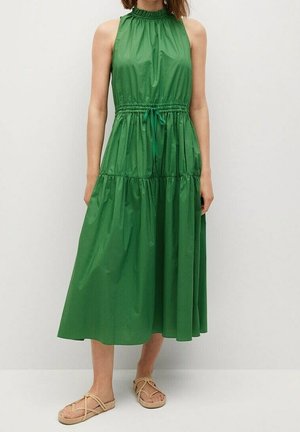 Vihreä ilmanhiha dressi, jossa on korkea kaula-aukko, kerätty vyötärö ja kerrostettupohja. Valmistettu kiiltävästä kankaasta, jossa on sileä rakenne, ja siihen kuuluu nyöri.