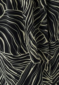 Tela negra con líneas beige audaces y en espiral formando un patrón abstracto. La textura parece suave, con pliegues que caen creando profundidad.