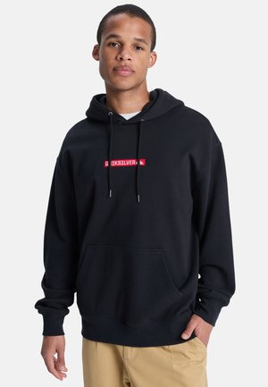 Black hoodie made of cotton with a front pouch pocket, adjustable drawstrings, and a red logo patch in the center. Classic fit.