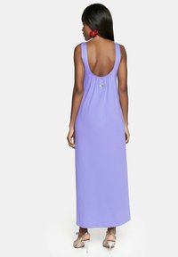 Długa lawendowa sukienka z dekoltem w serek, bez rękawów, z marszczeniem w talii. Gładka tkanina i długość do kostek.