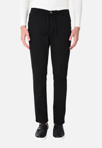 Pantaloni di cotone neri con chiusura a coulisse e bottone, design slim-fit, abbinati a scarpe slip-on nere. Tessuto liscio, stile casual.