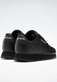 Sneaker nere in pelle con finitura testurizzata, caratterizzate da un profilo basso, suola in gomma e logo Reebok bianco sul tallone e sul lato.