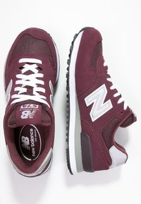 Scarpe da atletica in suede bordeaux con pannelli in rete, lacci bianchi e accenti grigi a contrasto. Caratterizzate da una suola intermedia imbottita e una suola esterna nera testurizzata.