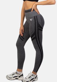 Szare legginsy z wysokim stanem, z czarnymi paskami akcentującymi i teksturowanym materiałem. Posiadają logo na udzie i dopasowany krój.