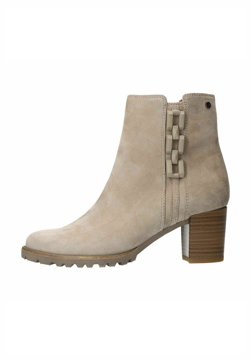 Beige Wildleder-Ankle-Boot mit einem dicken Absatz, ausgestattet mit einem dekorativen geometrischen Paneel an der Seite und einer Gummisohle für besseren Halt.