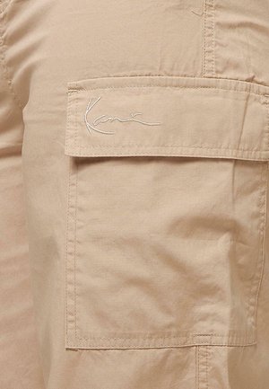 Beige cargoshorts met een zachte textuur, voorzien van een zijzak en een geborduurd logo op de zakklep. Duurzaam katoenmateriaal.