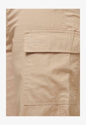 Bež kratke hlače s cargo žepi, mehke teksture, z bočnim žepom in izvezenim logotipom na jezičku žepa. Odporen bombažni material.