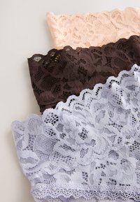 Trois échantillons de tissu en dentelle pliés en beige, marron foncé et gris clair avec des motifs floraux sur un fond neutre.