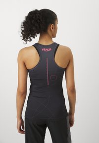 Crni atletski top s racerback dizajnom, s ružičastim "Venum" oznakama i geometrijskim linijama na leđima. Glatka tekstura.