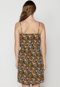 Vestido floral con tirantes finos, corpiño ajustado y falda acampanada. La tela oscura está adornada con coloridos patrones de flores y hojas.