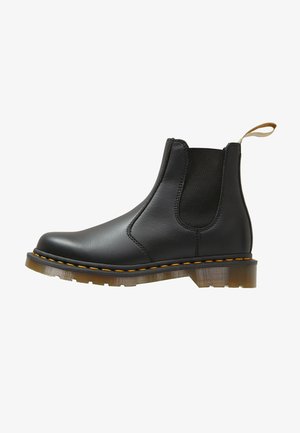 Black leather Chelsea boots with elastic side panels, a pull tab, and yellow stitching; featuring a translucent rubber sole.