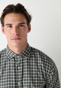 Hemd mit Knopfleiste und kariertem Muster in Beige, Grün und Marineblau. Verfügt über einen Kentkragen und eine leichte Stoffstruktur.