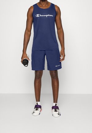 Navy tank top and shorts with a textured finish, featuring a prominent Champion logo. The model holds a black water bottle.
