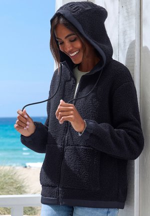Schwarze Fleece-Kapuzenjacke mit flauschiger Textur, Fronttaschen und verstellbarem Kordelzug. Reißverschluss und gerippte Bündchen für eine enge Passform.