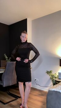 Czarna obcisła sukienka z koronkowymi długimi rękawami i wysokim kołnierzem. Projekt cechuje dopasowana sylwetka oraz teksturowane, przezroczyste detale na rękawach.