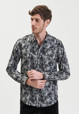 Camicia nera con bottoni, motivo floreale bianco, maniche lunghe e colletto classico. Tessuto morbido con un design aderente.