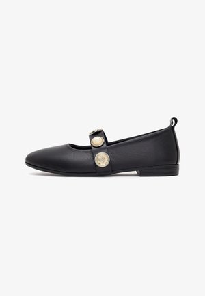Black flat Mary Jane shoe with decorative gold and pearl buttons on the strap and a small textured heel.